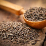 Caraway seeds in a spoon on wooden surface
